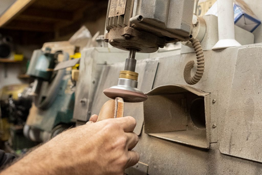 steve doudaklian using a machine to sand down the edges of the welt, midsole, and metal toe tap so they are flush