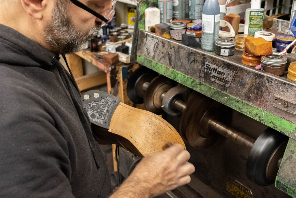 steve doudaklian of bedo's leatheworks applying a cream to the outsole of the shoe